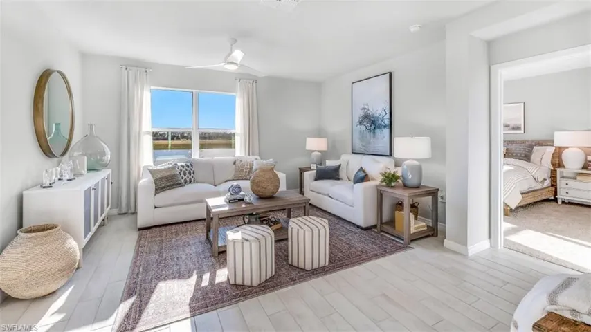 Model home. Living area with light wood-style flooring and a ceiling fan