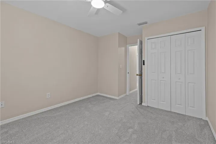 Unfurnished bedroom with light carpet, ceiling fan, and a closet
