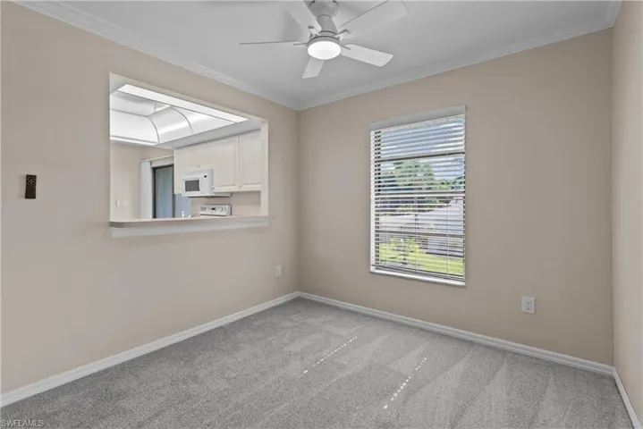 Empty room with ceiling fan, light carpet, and ornamental molding