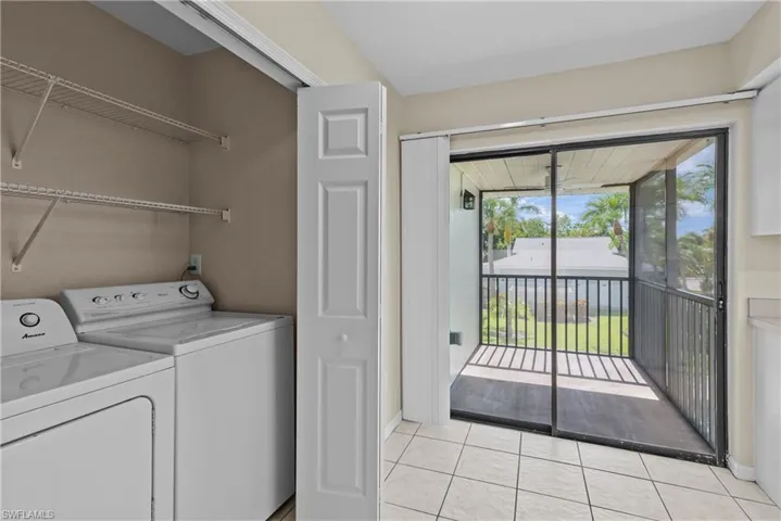 Clothes washing area with light tile patterned flooring and washer and dryer