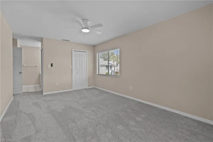 Unfurnished bedroom featuring a closet, light colored carpet, and ceiling fan