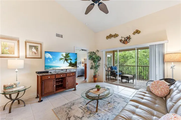 Living area with visible vents, high vaulted ceiling, light tile patterned floors, and a ceiling fan
