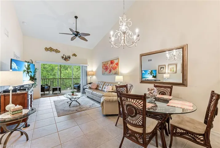 Dining space with high vaulted ceiling, visible vents, ceiling fan with notable chandelier, and light tile patterned flooring