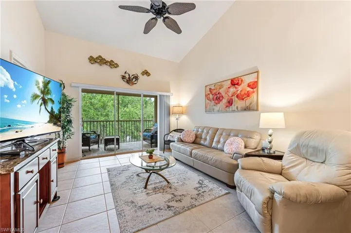 Living room with high vaulted ceiling, ceiling fan, and light tile patterned floors