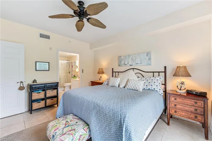 Bedroom featuring visible vents, ensuite bathroom, a ceiling fan, and light tile patterned flooring