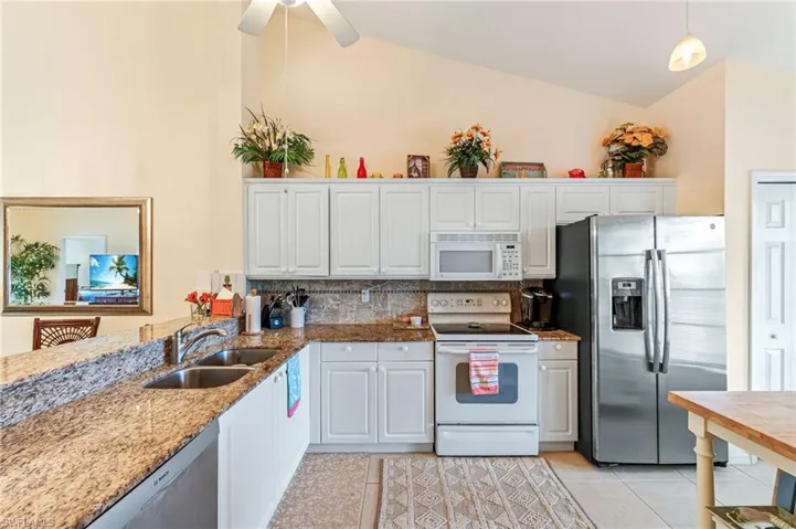 Kitchen featuring a sink, white cabinets, appliances with stainless steel finishes, and vaulted ceiling