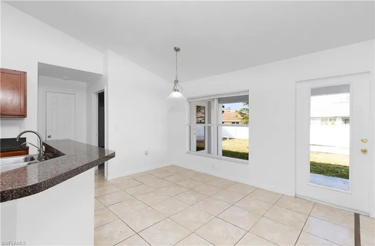 Unfurnished dining area with light tile patterned flooring, sink, and vaulted ceiling