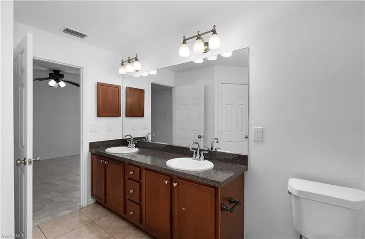 Bathroom with tile patterned floors, vanity, toilet, and ceiling fan