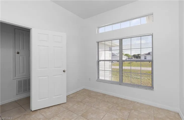 Unfurnished room with lofted ceiling and light tile patterned flooring