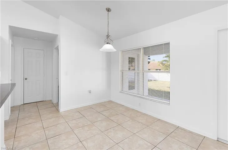 Unfurnished dining area with light tile patterned floors and vaulted ceiling