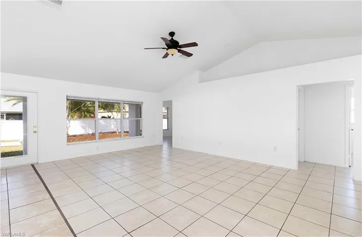 Tiled spare room featuring ceiling fan and vaulted ceiling
