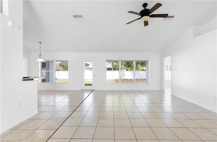 Unfurnished room with a wealth of natural light, light tile patterned flooring, high vaulted ceiling, and ceiling fan
