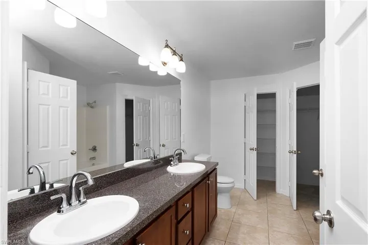 Full bathroom with tile patterned floors, vanity, toilet, and shower / bath combination