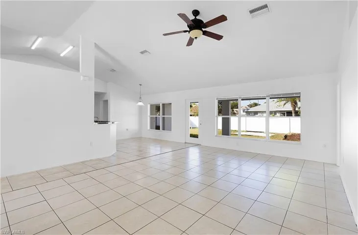 Unfurnished living room featuring light tile patterned floors, ceiling fan, and lofted ceiling