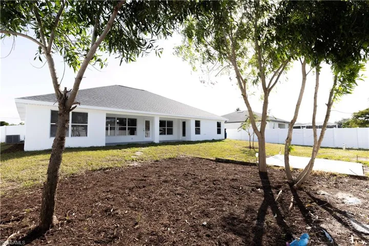 Back of property with a lawn and central AC