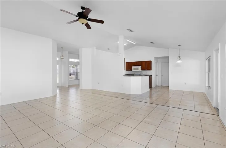 Unfurnished living room with ceiling fan, light tile patterned floors, and vaulted ceiling