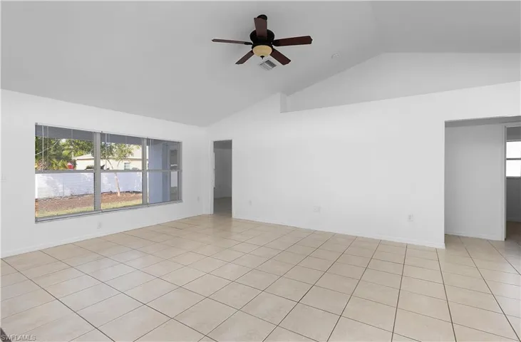 Tiled spare room with ceiling fan and lofted ceiling