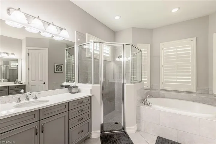 Bathroom featuring vanity, a stall shower, a bath, and light tile patterned floors