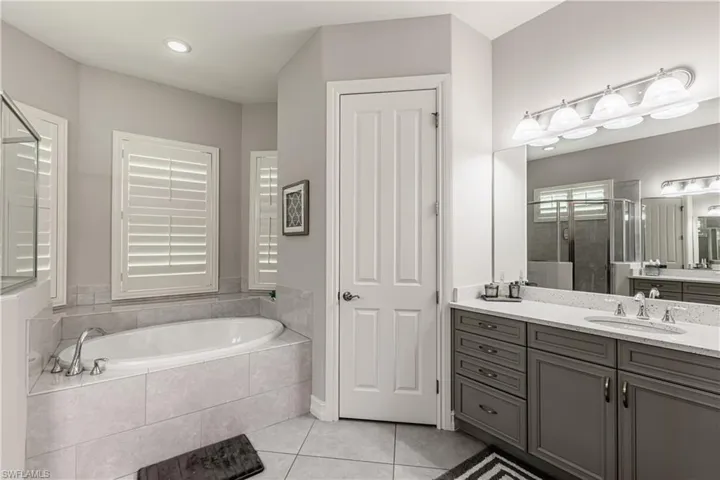 Full bath featuring vanity, a shower stall, light tile patterned flooring, and a bath