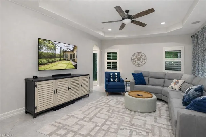 Living room featuring a tray ceiling, arched walkways, ceiling fan, and recessed lighting
