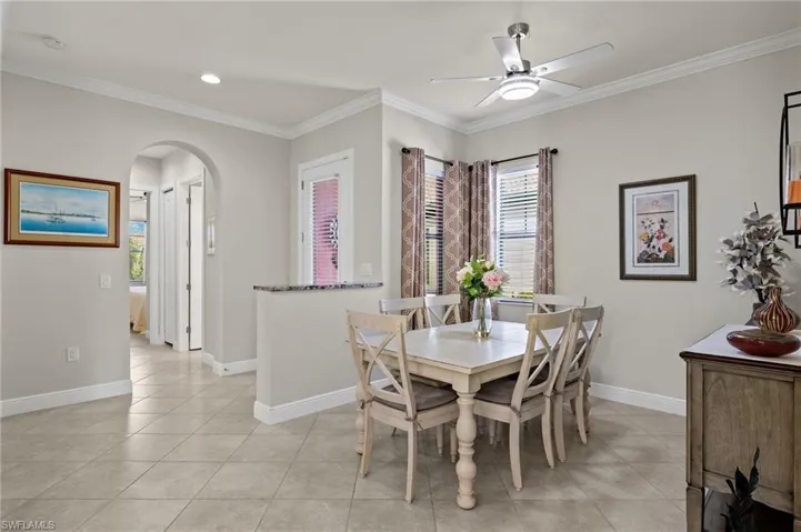 Light and bright dining room featuring ornamental molding, light tile flooring, and ceiling fan.
