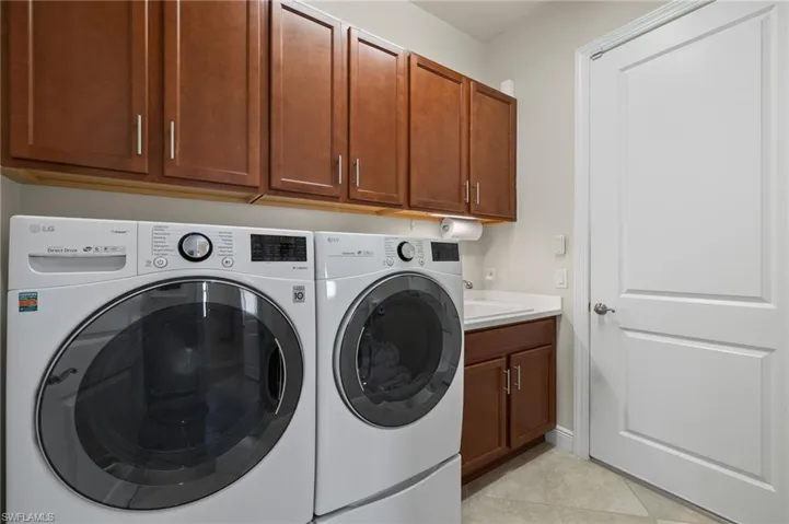 Laundry room featuring cabinets, upgraded LG washer and dryer, light tile floors and a sink!
