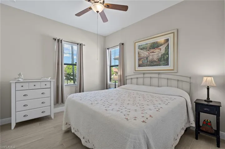Light and bright guest Bedroom featuring a kingsize bed, light tile floors and ceiling fan.
