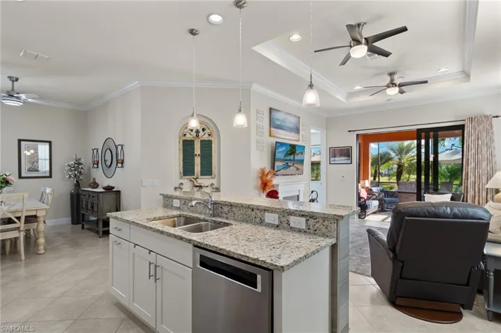 Kitchen with upgraded stainless steel appliances, an island/bar, white cabinetry, decorative pendant light fixtures, and light granite counters.