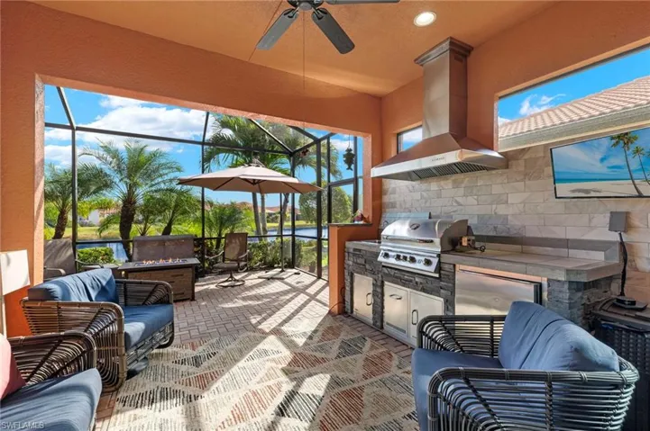 Outdoor kitchen with tile counter and backsplash, plenty of seating, ceiling fan, noseeum screened lanai and beautiful lake views.