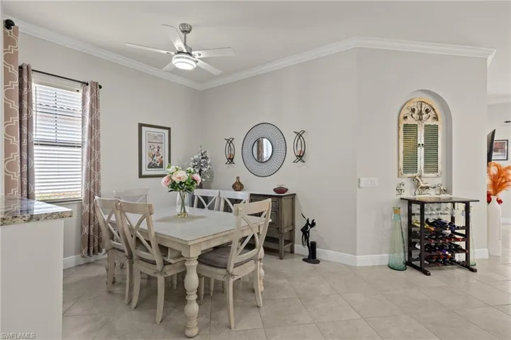 Light and bright dining room featuring ornamental molding, light tile flooring, and ceiling fan.