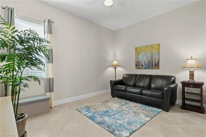 Light and bright den with a queen size sleeper sofa, light tile flooring, and ceiling fan.