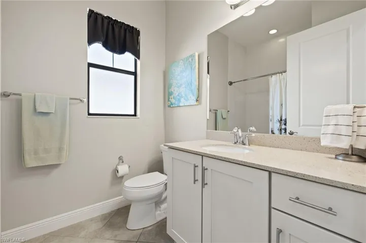 Guest Bathroom featuring a tiled shower/tub, vanity, and light tile flooring.