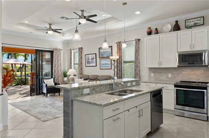 Kitchen with upgraded stainless steel appliances, an island/bar, white cabinetry, decorative pendant light fixtures, granite counters and tranquil lake views.