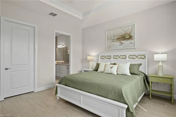 Primary Bedroom featuring tray ceiling, crown molding, ceiling fan, light tile floors, king size SLEEP NUMBER bed and large walk-in closet.