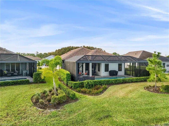 Back of property featuring a patio, a lanai, a lawn, and a pool