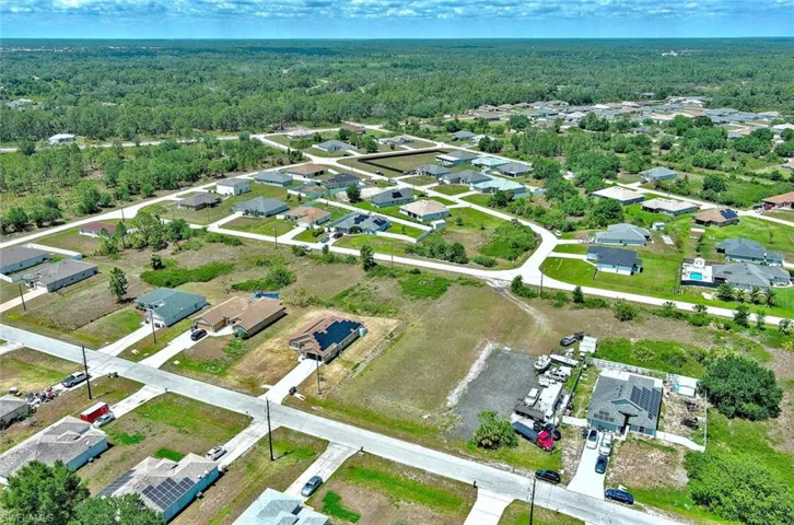 View of property location featuring a heavily wooded area and nearby suburban area
