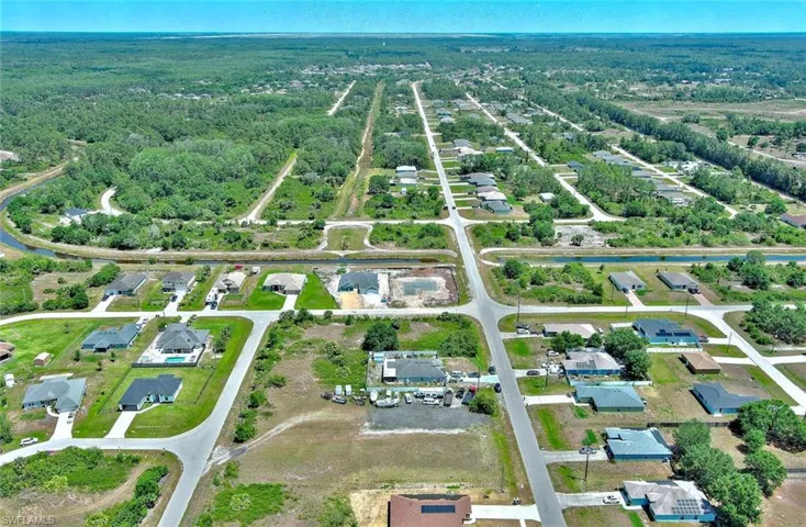 Aerial view of property and surrounding area with nearby suburban area and a heavily wooded area