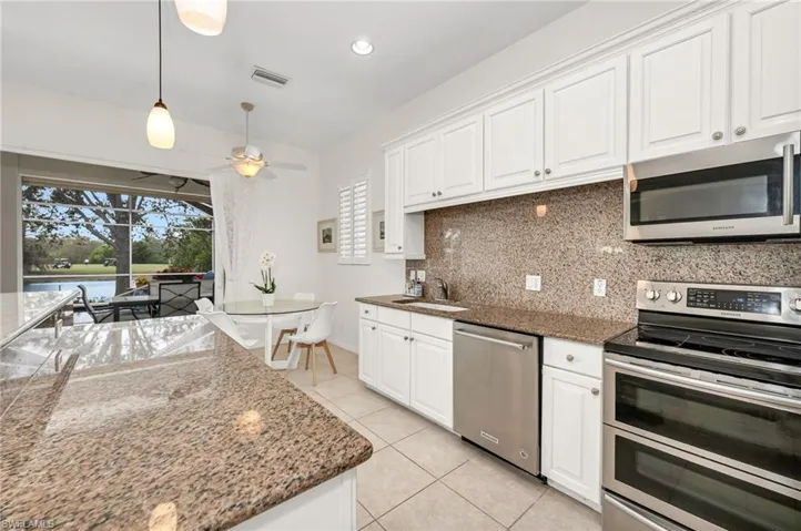 Spacious and open kitchen with white cabinetry and ample counter space.