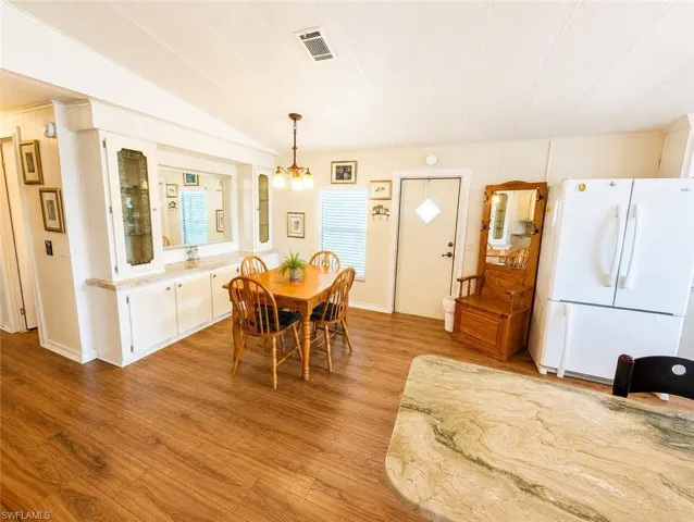 Open-concept dining space featuring wood-finish flooring, a built-in buffet with mirrored backsplash, and an overhead chandelier