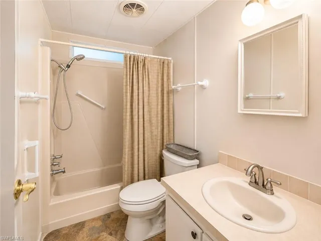 Full bathroom featuring a combined tub and shower unit, a single-sink vanity with a laminate countertop, and tiled flooring