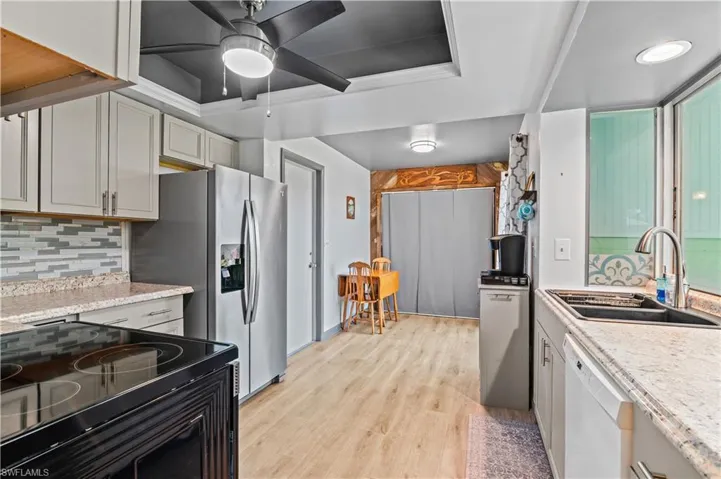Kitchen with electric range, backsplash, light wood-style flooring, dishwasher, and a ceiling fan