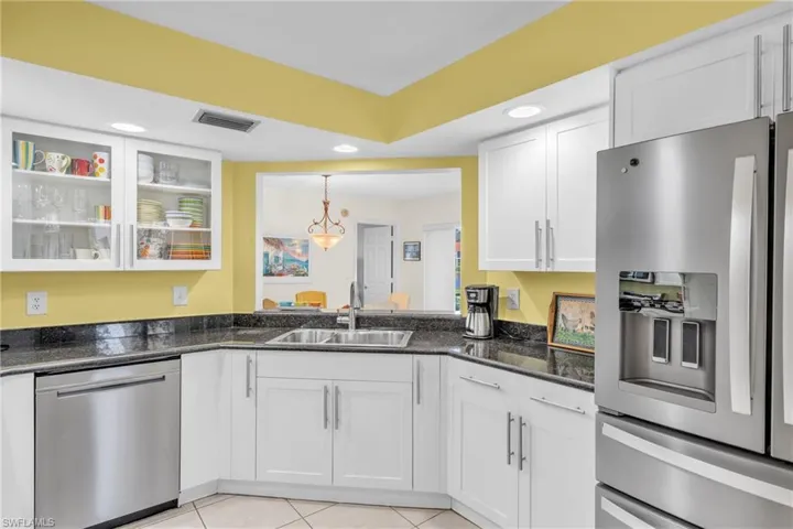 Modern kitchen featuring white shaker-style cabinetry with chrome hardware, stainless steel appliances including a French-door refrigerator with ice and water dispenser, and a gas cooktop