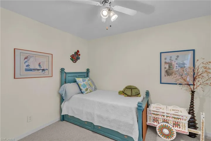 Charming bedroom featuring a turquoise wooden bed frame with coordinating posts, carpet flooring, and soft cream-colored walls