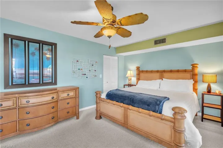Carpeted bedroom featuring a ceiling fan with integrated lighting, a built-in air vent, and a two-tone painted wall design