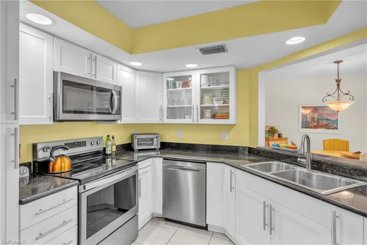 Bright and functional kitchen featuring white cabinetry with stainless steel appliances, including a built-in microwave, electric range, and dishwasher