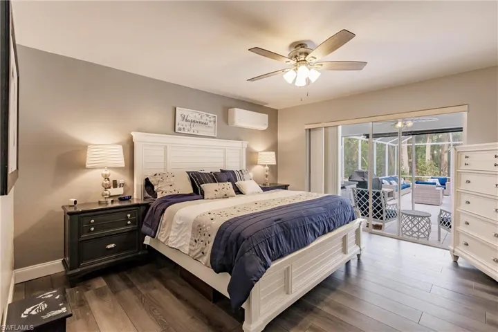 Bedroom featuring dark wood-type flooring, ceiling fan, an AC wall unit, and access to outside