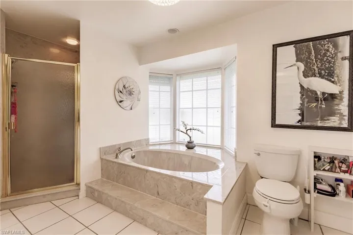 Bathroom with separate shower and tub, toilet, and tile floors