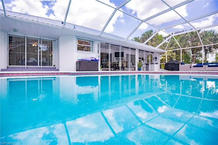 View of swimming pool featuring glass enclosure, a patio area, and area for grilling