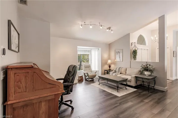 Office space with track lighting, an inviting chandelier, dark hardwood / wood-style floors, and vaulted ceiling