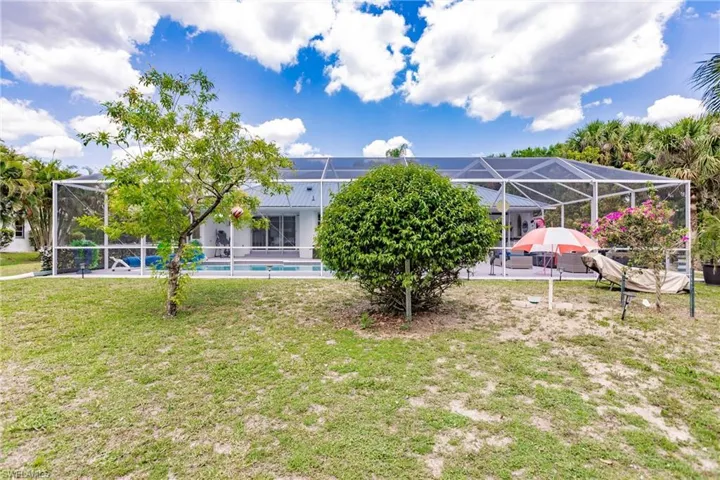 Rear view of property featuring a patio area, a lawn, and a lanai